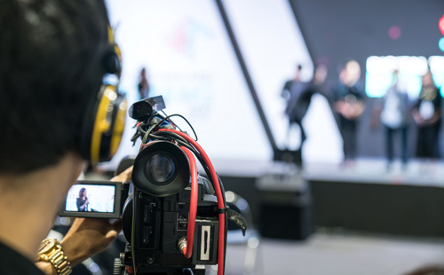man using a video camera to film an event on stage