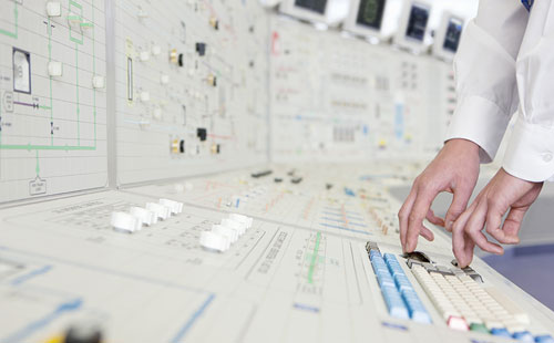 technician's hands at nuclear reactor control board