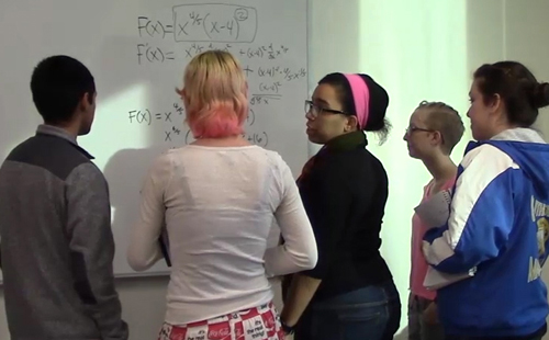 一位学习助手(中)在微积分课堂上指导一群学生。